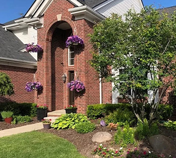 a house with bushes in front of a brick building